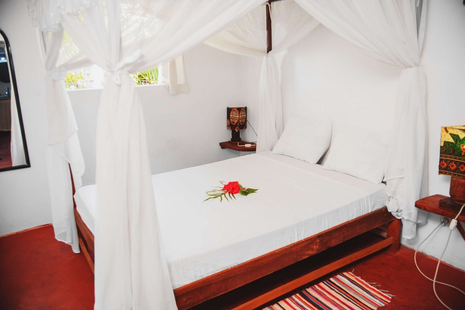 Chambre d'une villa Piment Vanille : lit à baldaquin blanc et fleur d'hibiscus